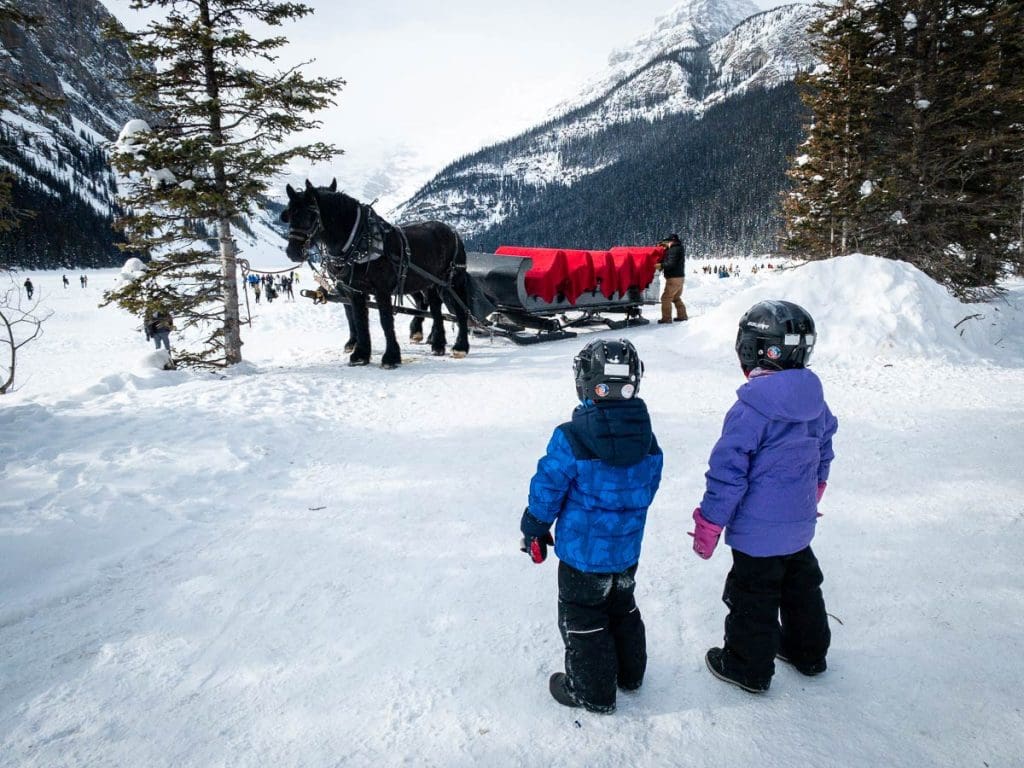 two kids look at the horse drawn sleigh at Lake Louise.