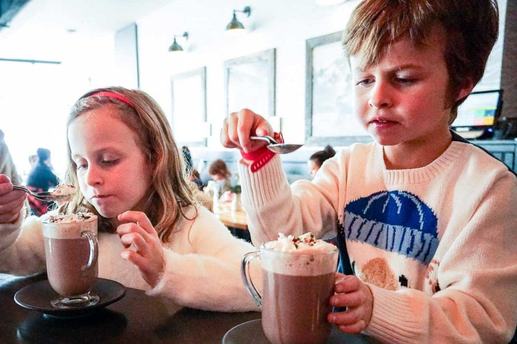 two kids have hot chocolate at Sky Bistro at Banff Gondola.