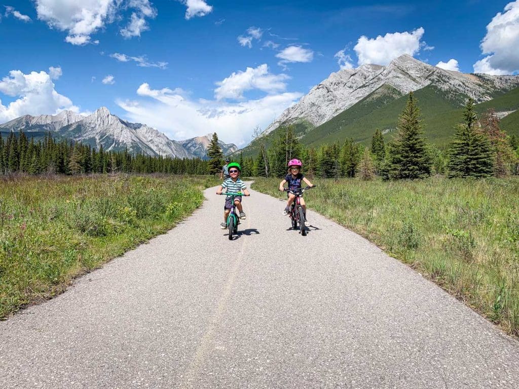 Two kids biking on the paved bike paths in Canmore.