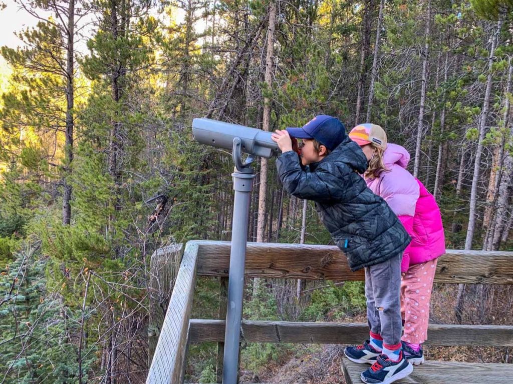 A boy and girl look through a telescope along the boardwalks at the Cave and Basin in Banff National Park.