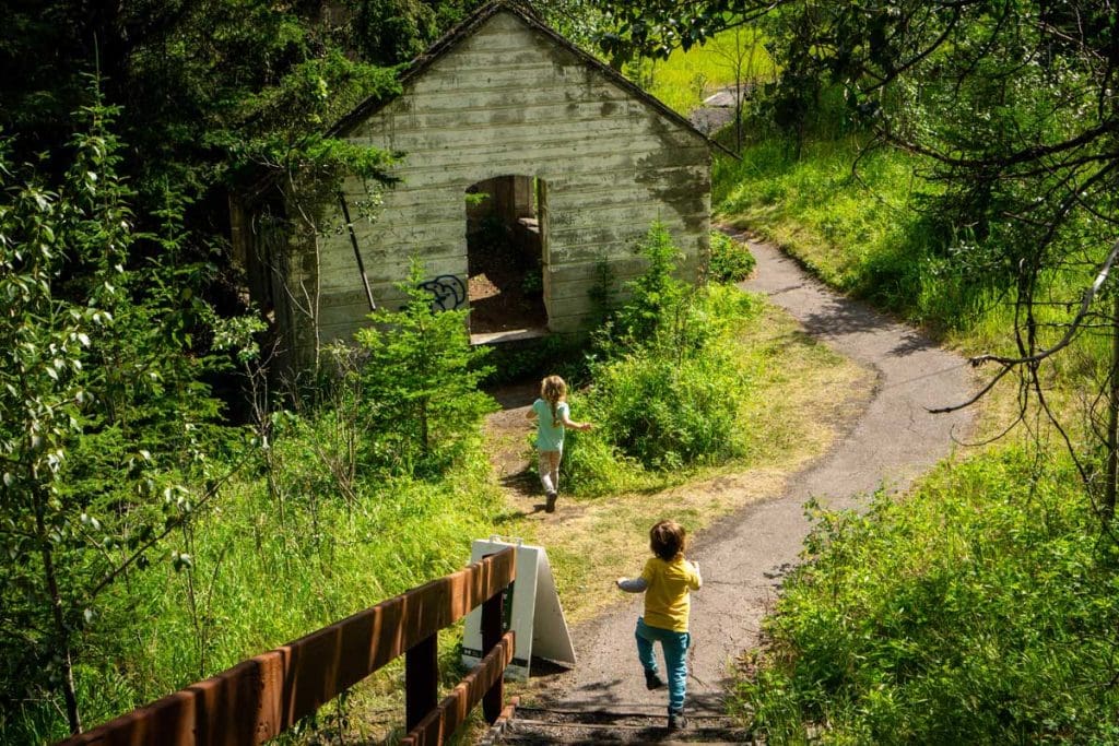 two kids run down a hill towards an abandoned building at Lower Bankhead in Banff.