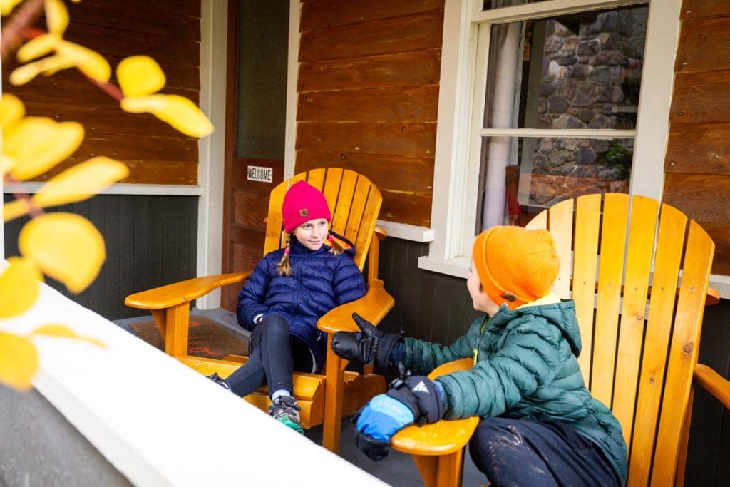 two kids sitting on chairs outside of Johnston Canyon Cabins in Banff National Park.