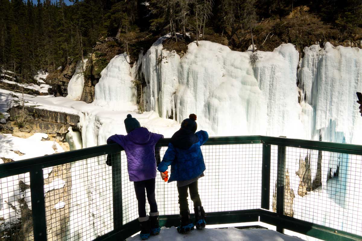 Two kids look at Frozen Waterfalls at Johnston Canyon