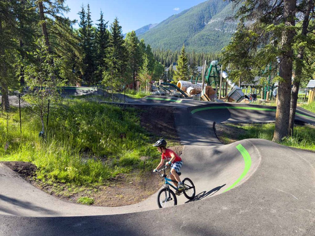 a 10-year old boy rides his BMX bike on the Banff Pump Track on a sunny morning in August.
