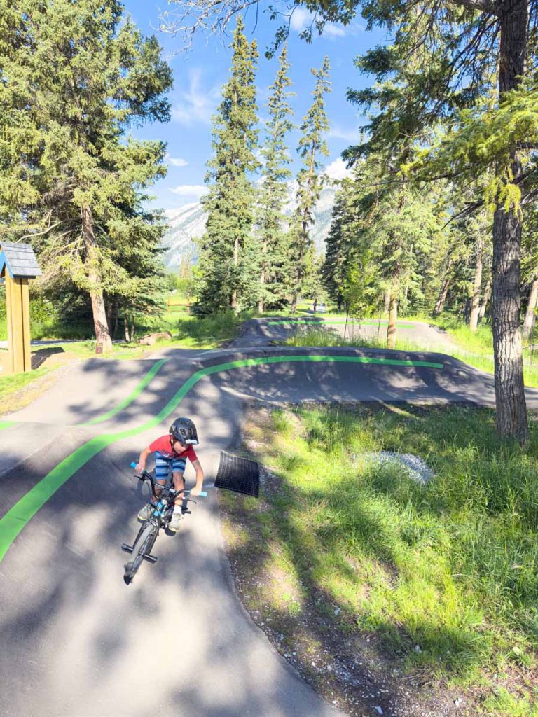 a young boy enjoys riding his BMX around the Banff Pump Track in August.