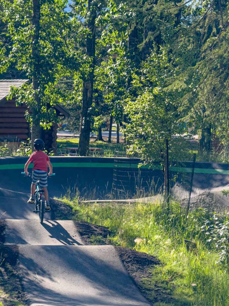 a 10-year old boy rides his bike around the Banff Pump Track.