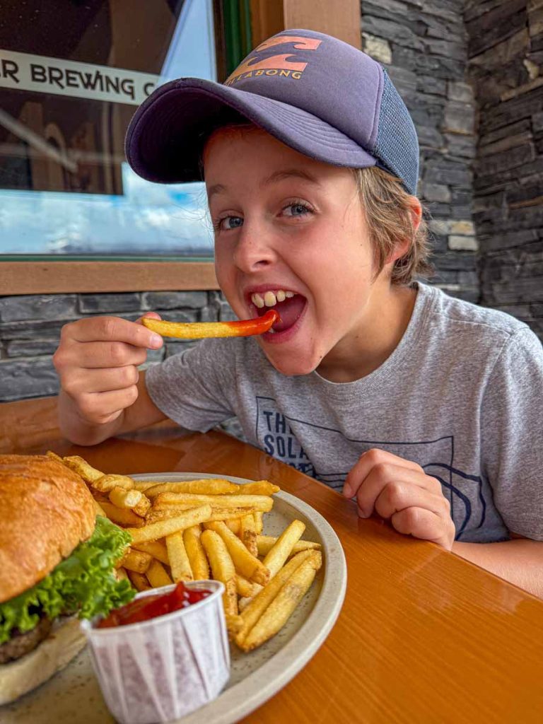 a 10-year old boy eats a hamburger at the Jasper Brewing Company.